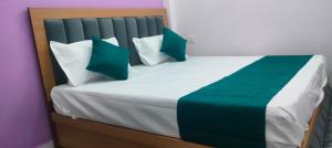 a bed with green and white pillows on it at Hotel Dharma palace in Prayagraj