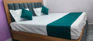 a bed with green and white pillows on it at Hotel Dharma palace in Prayagraj +7 photos