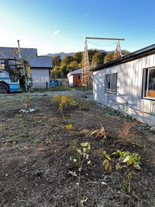 a yard with a building and a windmill at Kutral-Ko in Hornopiren