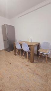 a wooden table with two chairs and a refrigerator at Downtown City Apartment in Râmnicu Vâlcea +6 photos