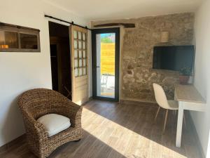 a room with a chair and a table and a television at Le Moulin de Lauve in Saint-Hilaire-les-Courbes