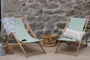 two rocking chairs sitting next to a stone wall at Le Moulin de Lauve in Saint-Hilaire-les-Courbes