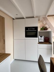 a kitchen with white cabinets and a black appliance at BLUSH Bed and Breakfast in Sprundel