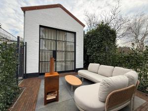 a patio with a couch and a chair and a table at BLUSH Bed and Breakfast in Sprundel
