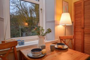 a table with two cups and a vase on it with a window at Montford Shore in Rothesay +14 photos