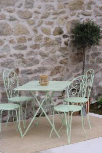 a white table and chairs next to a stone wall at Le Moulin de Lauve in Saint-Hilaire-les-Courbes