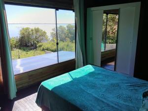 a bedroom with a bed and a large window with a tub at Casa da Lagoa perto do Mar in Pescaria Brava +38 photos