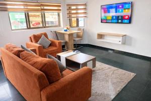 a living room with two chairs and a tv at Sky Suites East Legon in Accra