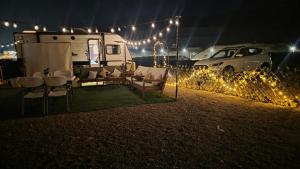 a table and chairs in front of a trailer at night at Happy dreams in Ramlah
