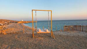 a swing on the beach next to the ocean at Happy dreams in Ramlah