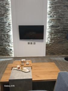 a living room with a table and a flat screen tv at Dipotamata House SynetI in Andros
