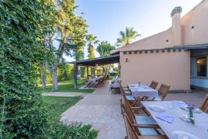 a patio with tables and chairs and trees at Villa Carlotta Resort in San Leone