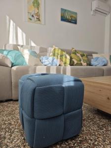 ein blauer Ottoman in einem Wohnzimmer mit einem Sofa in der Unterkunft SeaSuites Blue-Ático con terraza chillout cerca del mar en Cullera in Mareny de San Lorenzo