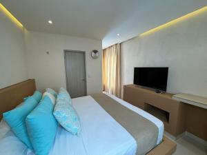 ein Schlafzimmer mit einem Bett mit blauen Kissen und einem Fernseher in der Unterkunft Techos Azules in Taganga + 82 Fotos