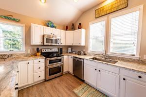 a kitchen with white cabinets and stainless steel appliances at Family Tradition - Duck Landing, Oceanside, 130 Yds to Beach, Pool, Hot Tub, Tiki Bar in Duck