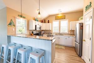 a kitchen with white cabinets and blue stools at Family Tradition - Duck Landing, Oceanside, 130 Yds to Beach, Pool, Hot Tub, Tiki Bar in Duck