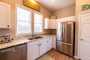 a kitchen with white cabinets and a stainless steel refrigerator at Family Tradition - Duck Landing, Oceanside, 130 Yds to Beach, Pool, Hot Tub, Tiki Bar in Duck