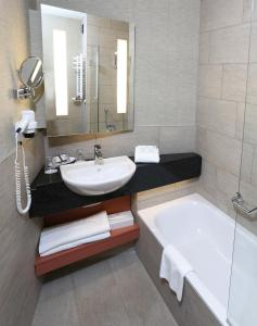 a bathroom with a tub, sink, and mirror at Ensana Thermal Aqua in Hévíz