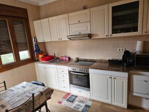 a kitchen with white cabinets and a table in it at Casa da Cabreira in Nigrán +4 photos