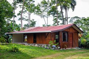 a small wooden house with a red roof at Casa Cúrcuma in Turrialba