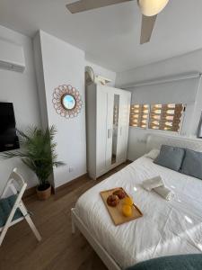 a white bedroom with a tray of food on a bed at Vacaciones en familia Ap Portitxol en Xàbia in Platja de l'Arenal