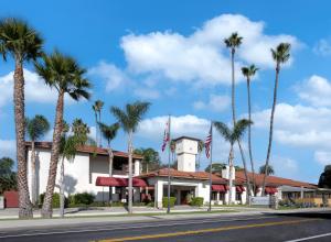 a building with palm trees in front of a street at Clocktower Inn Ventura in Ventura
