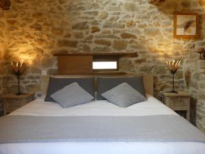 a bedroom with a white bed with a stone wall at Studio Natur'ailes, Le Hameau du Quercy, romantique, campagne, piscine naturelle in Frontenac