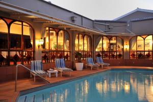 a hotel swimming pool with two chairs and a building at Cumberland Hotel & Conference Centre Worcester in Worcester
