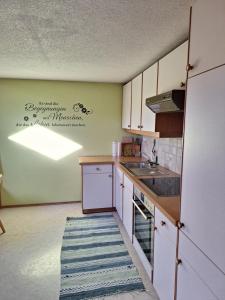 a kitchen with white cabinets and a sink at Ferienhof Muxel in Großdorf +5 photos