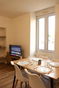 a dining room with a table with chairs and a tv at Le Nid de la Mayenne in Mayenne +6 photos