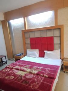 a bedroom with a large bed with a red headboard at Mall City Hotel Lahore in Lahore
