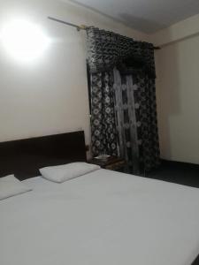 a bedroom with a white bed and a curtain at Mall City Hotel Lahore in Lahore