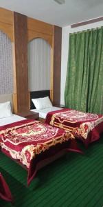 two beds sitting in a room with green carpet at Mall City Hotel Lahore in Lahore