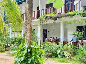 people sitting on the balcony of a building with a palm tree at Sigiri Rainbow Lodge in Sigiriya