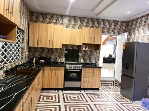 a kitchen with wooden cabinets and a black refrigerator at AnKeS Lodge in Sunyani