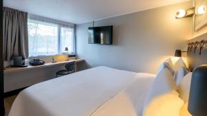 a hotel room with a bed and a desk and a window at Campanile NATURE - Niort Est La Crèche in La Creche