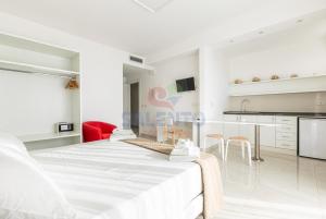 a white bedroom with a large bed and a kitchen at Residence Stella del Mare in Torre Pali