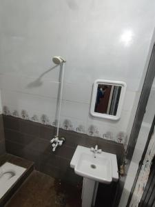 a bathroom with a sink and a mirror and a toilet at Second Home Hotel in Multan