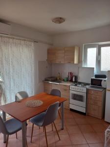 a kitchen with a wooden table and chairs and a table and a stove at Apartmani Antonio Basina in Vrbanj