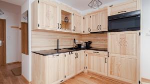 a kitchen with wooden cabinets and black counter tops at Apartament Białka J6 in Białka Tatrzańska +11 photos