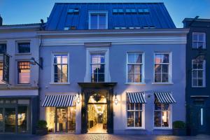 een groot wit gebouw met een winkelpui bij The Saints Bliss Hotel in Breda