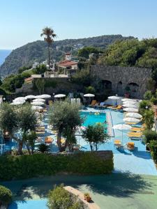 a resort with a pool with chairs and umbrellas at Sunlux Maison in Forio d'Ischia