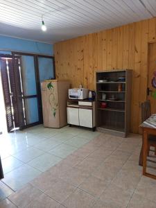 a kitchen with wooden walls and a refrigerator and a table at Kitnet simples in Capão da Canoa