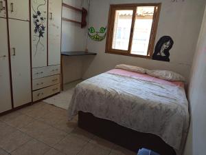 a small bedroom with a bed and a window at Kitnet simples in Capão da Canoa