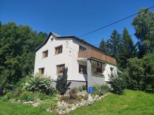 a white house with a balcony on a hill at Přijďte pobejt in Benecko