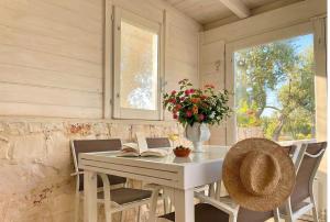 a table and chairs with a book and a vase of flowers at Dimora Antonella - Ostuni 4 seasons - Splendid Villa Depandance with Private Swimming Pool in Ostuni