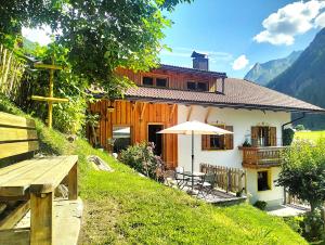 a house with a table and an umbrella in front of it at B&B Luggla - sauna in camera in Predoi