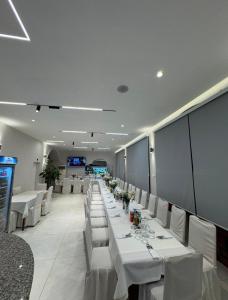a long dining room with white tables and white chairs at Hotel Bar-Restorant Fresku in Fushë-Arrëz