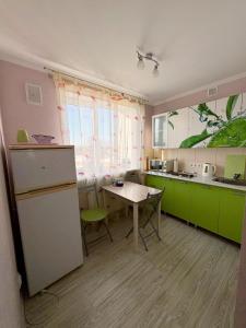 a kitchen with green cabinets and a table in it at Liudmila in Liepāja