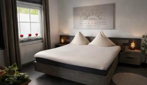 a bedroom with a bed with white sheets and a window at Wellnesshaus - Whirlpool - Sauna - Relax in Herten